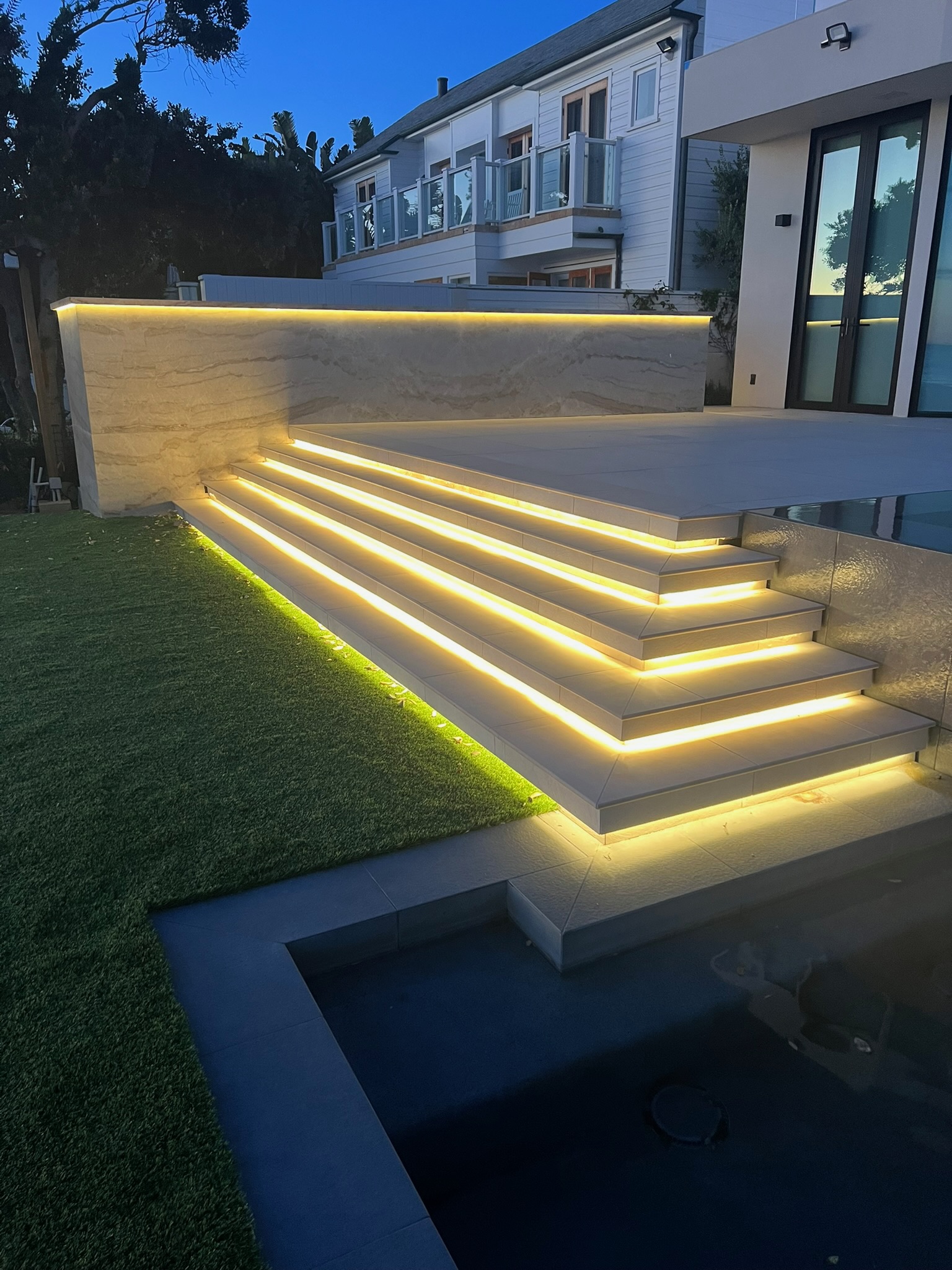 Backlit translucent travertine wall and illuminated stone stair treads on a luxury residential exterior by LIT Group, Los Angeles.
