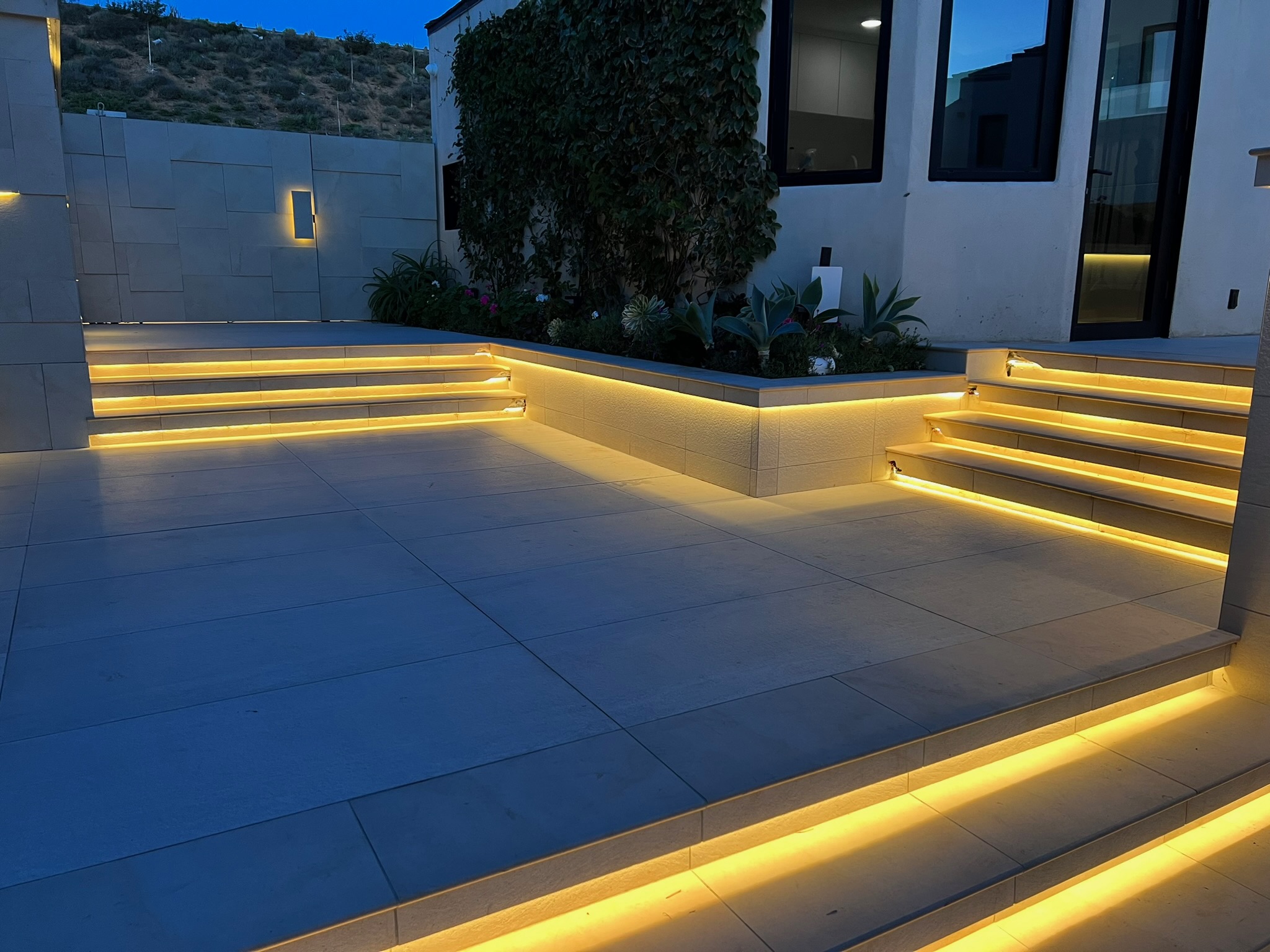 Finished concealed linear LED lighting at concrete steps and planter on a luxury residential build by LIT Group.