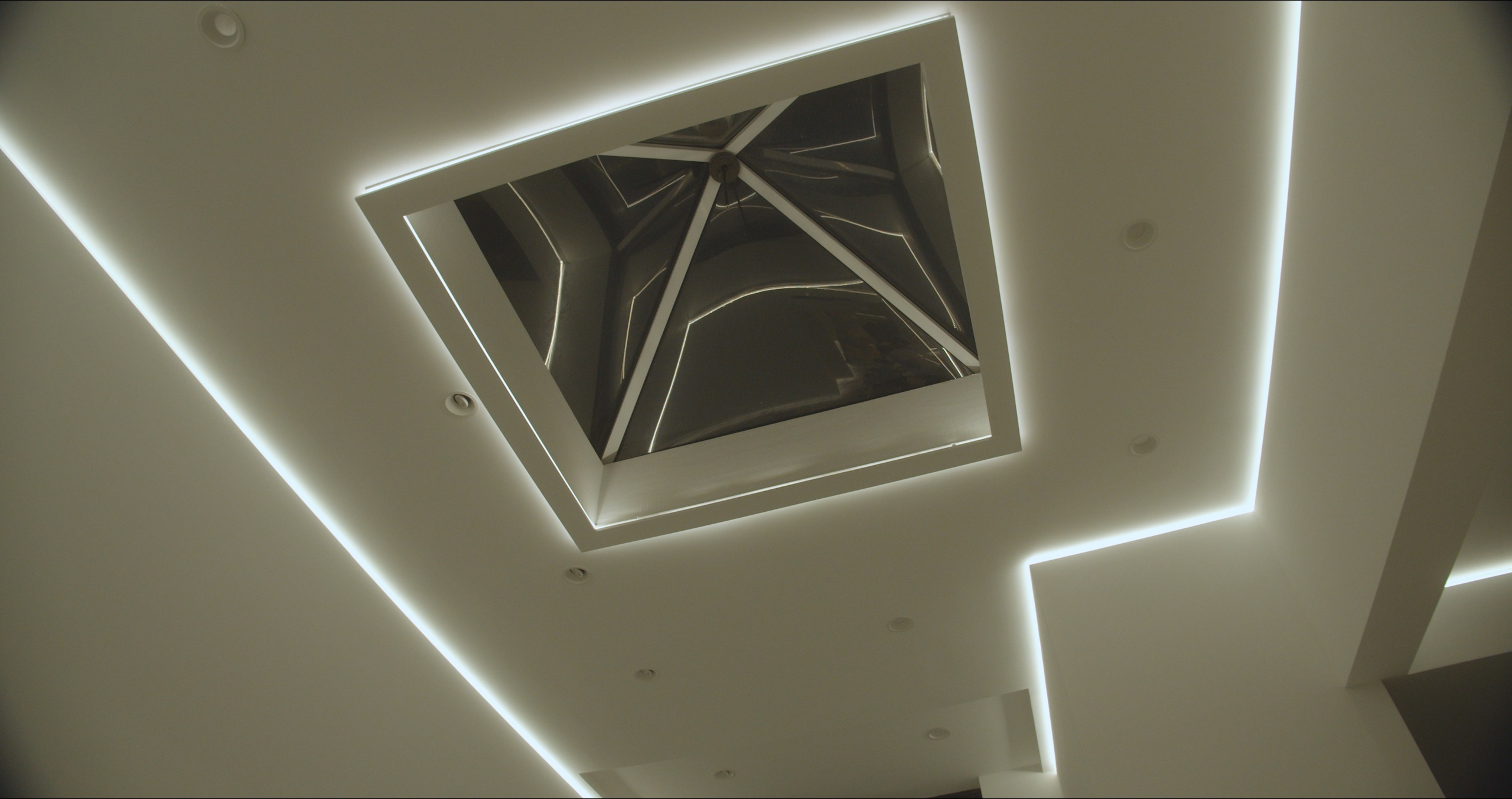 Concealed reveal and cove lighting framing a feature ceiling skylight &mdash; specified design intent executed by LIT Group.